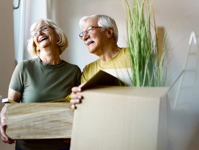 Happy mature couple packing their belongings before moving out of their apartment.