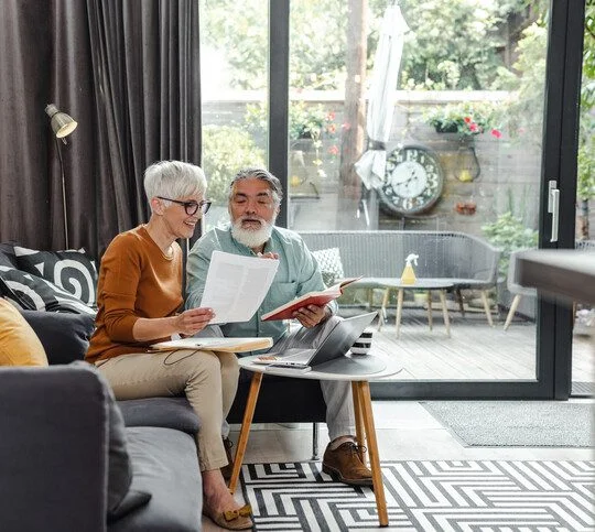 Senior couple discussing home finances and using laptop