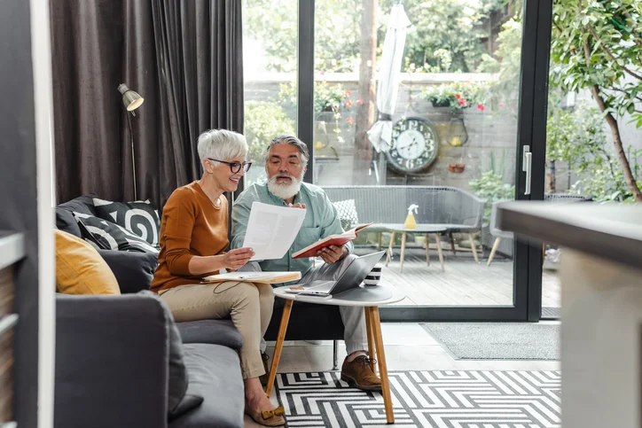 Senior couple discussing home finances and using laptop