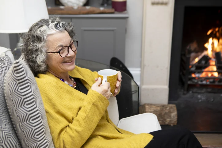 Smiling mature woman sitting on a sofa with a coffee