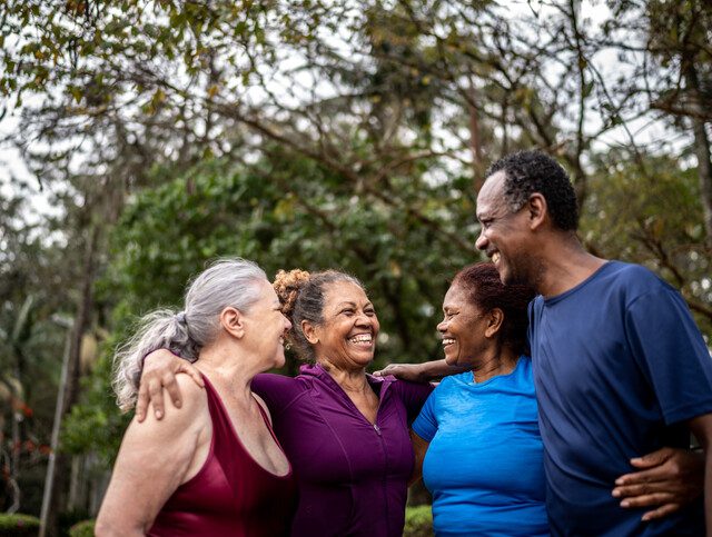 Happy senior friends embracing in a park.