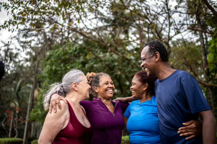 Happy senior friends embracing in a park.