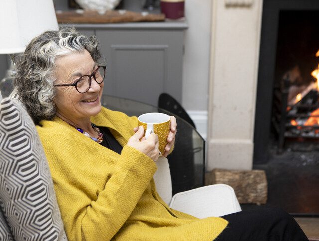 Smiling mature woman sitting on a sofa with a coffee
